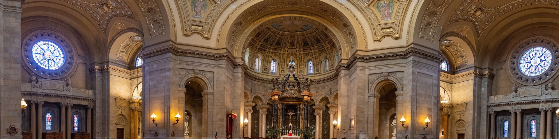 An ornate church interior with high ceilings, detailed arches, and stained glass windows.