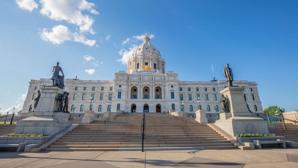 A large government building with a dome and statues in front.