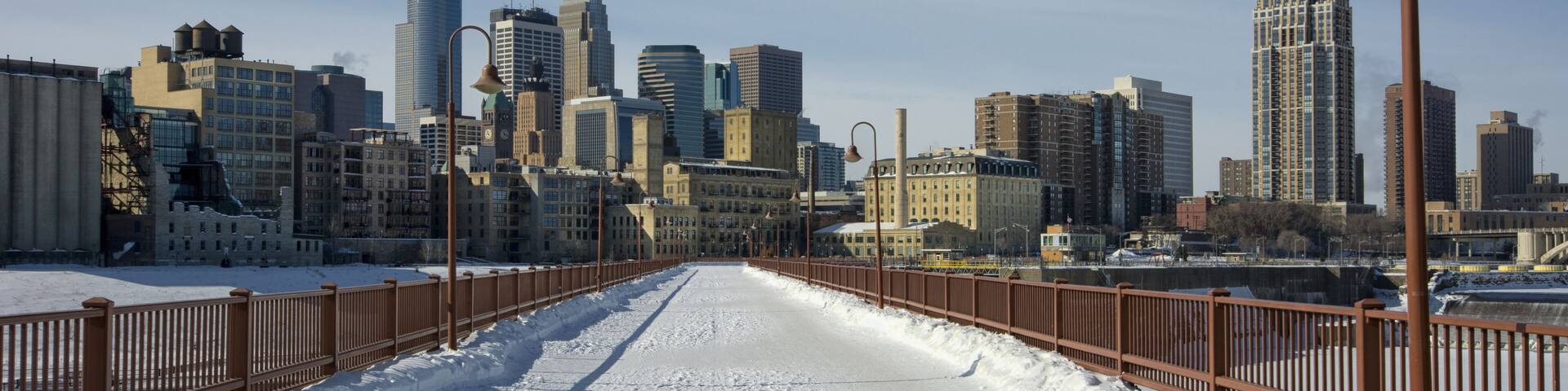 A snow-covered pathway leading to a city skyline with modern buildings.
