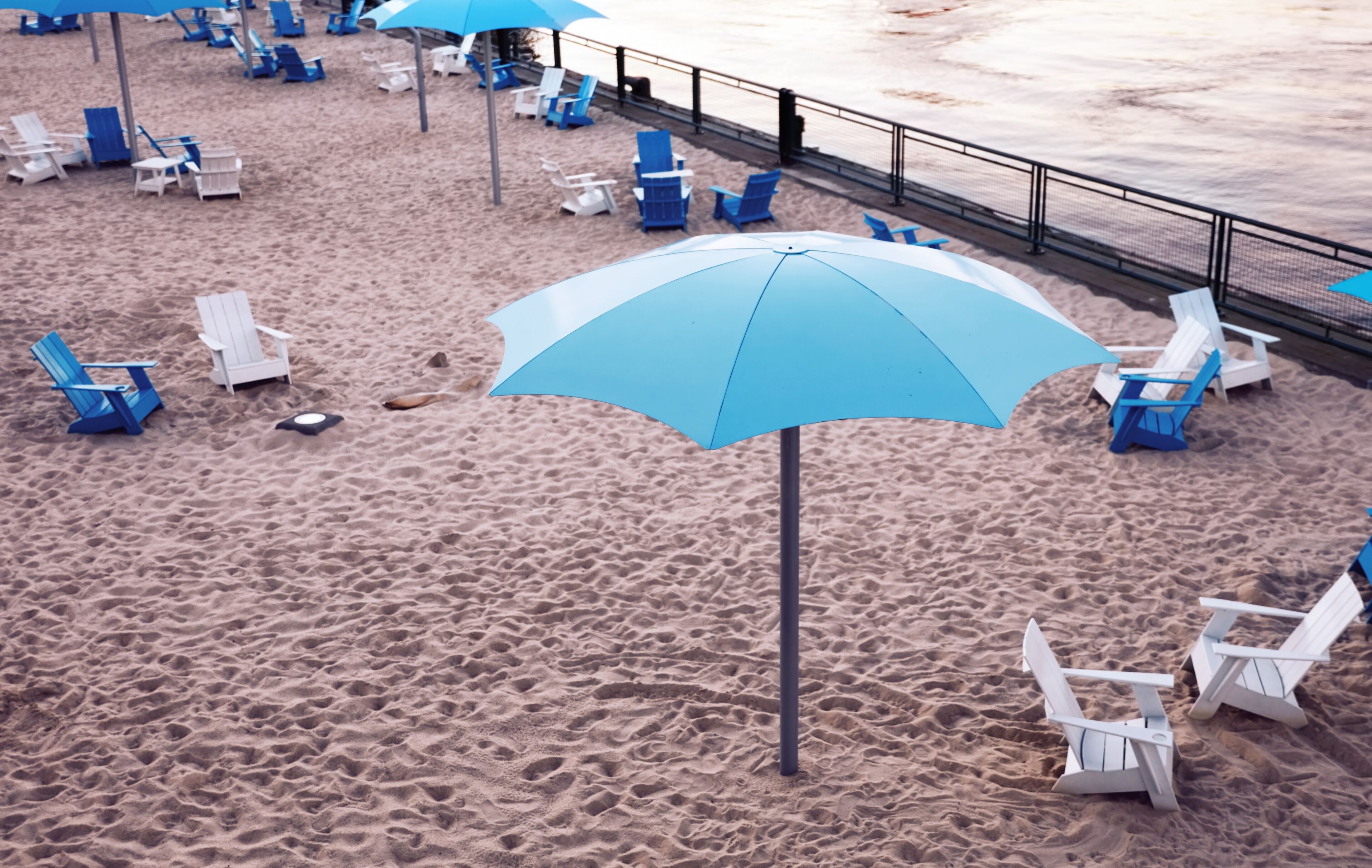 Una playa con sillones y sombrilla azules y blancos.