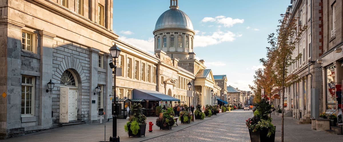 A cobblestone street lined with historic buildings and a prominent dome structure in the background.
