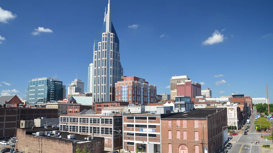 A cityscape with a prominent skyscraper, various commercial buildings, and a clear blue sky.