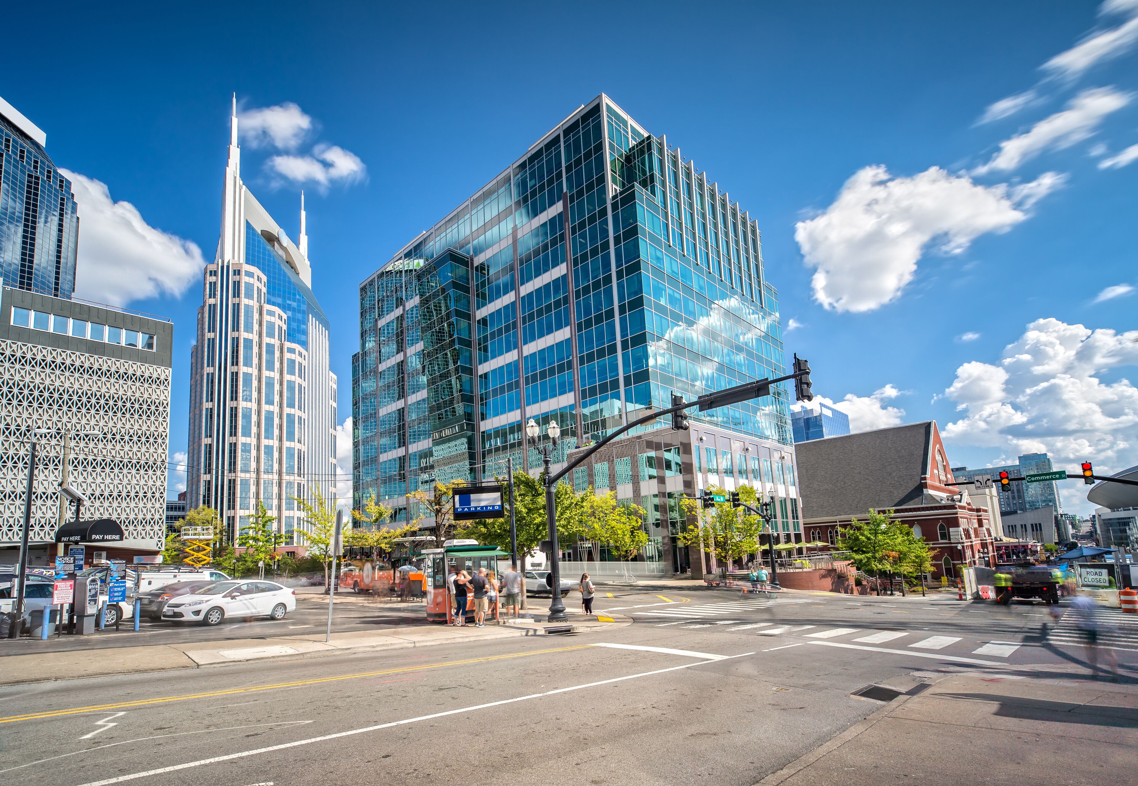 A city intersection with modern buildings, a bus stop, and a traffic light.