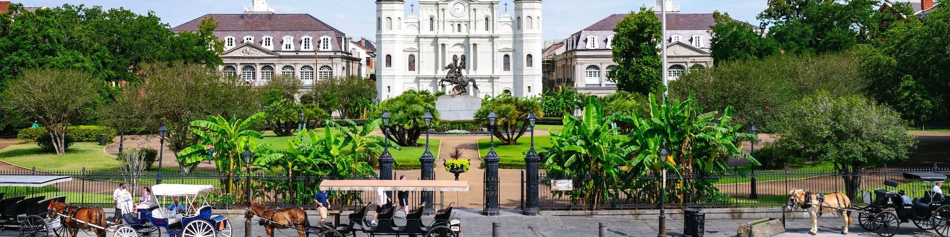 A historic church with three spires, surrounded by lush greenery and a flagpole with an American flag.