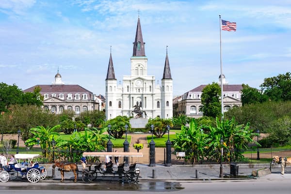 Eine historische Kirche mit drei Türmen, umgeben von üppigem Grün und einer Fahnenstange mit der US-amerikanischen Flagge.