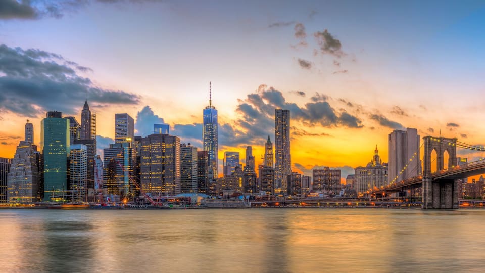 A city skyline with a prominent bridge at sunset.