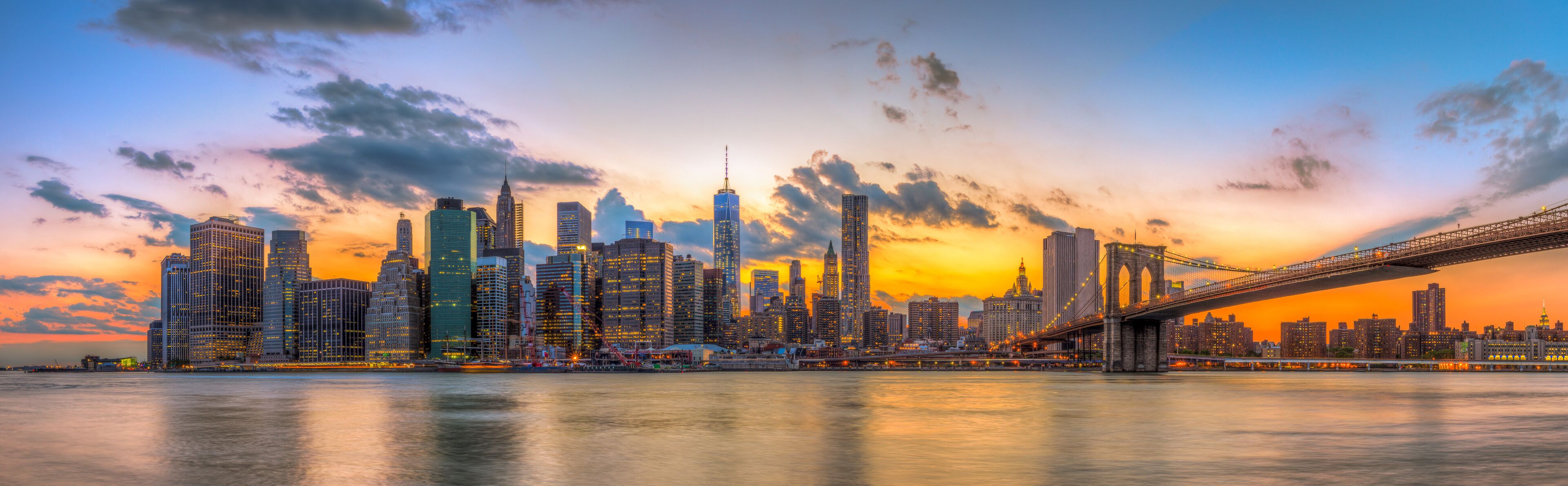 A city skyline with a prominent bridge at sunset.