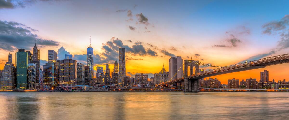 A city skyline with a prominent bridge at sunset.