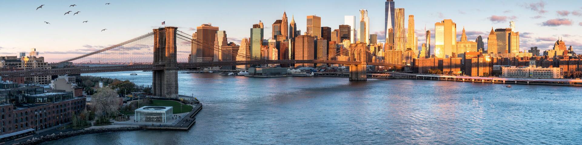 A city skyline with a prominent bridge spanning a river, surrounded by modern skyscrapers and historic buildings.