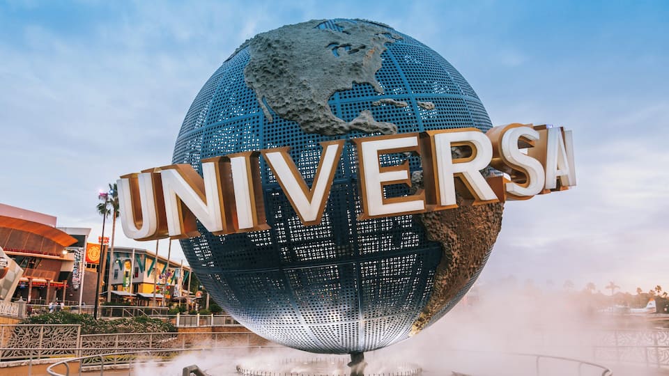 A large globe with the word "UNIVERSAL" on it, surrounded by a fence and a fountain.
