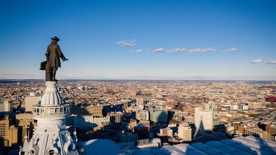 A statue on a building with a cityscape in the background.