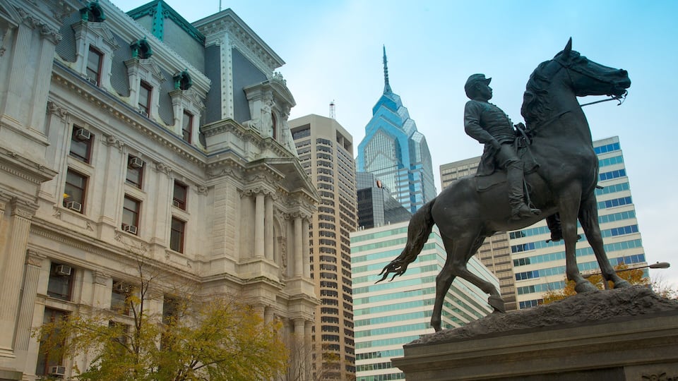A statue of a man on a horse in front of a historic building with modern skyscrapers in the background.