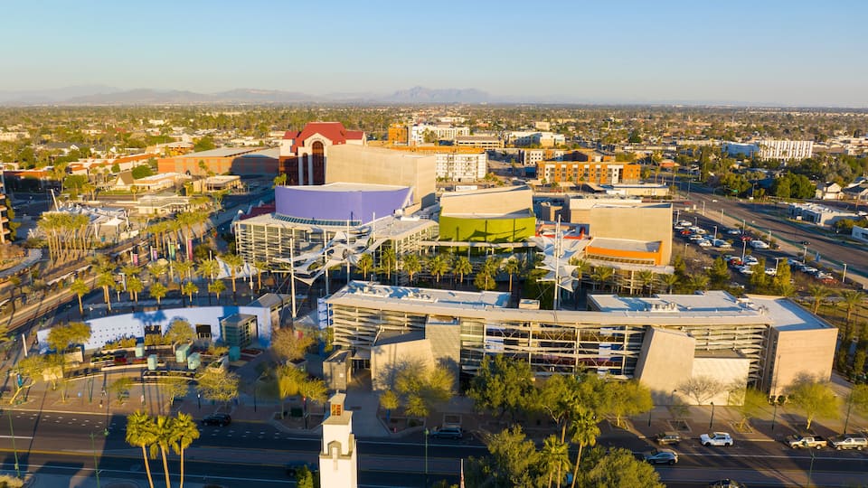 An aerial view of a cityscape with modern architecture, including a distinctive building with a red roof and a white tower.