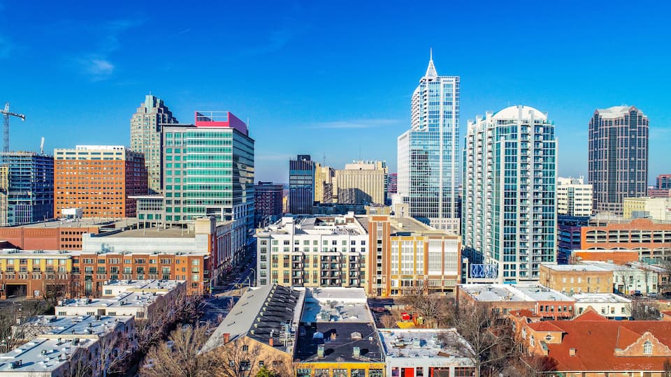 A cityscape with modern high-rise buildings, a mix of commercial and residential structures, and a clear blue sky.