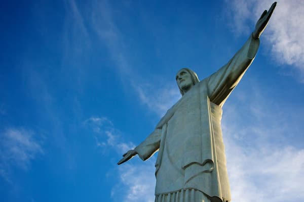 Uma estátua com braços estendidos contra um céu azul.