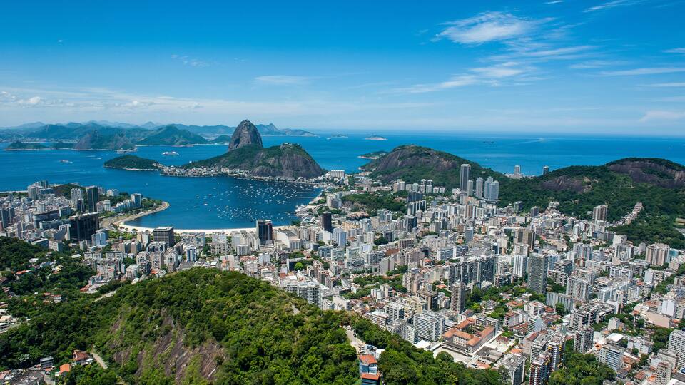 A coastal cityscape with a prominent mountain and a bay.