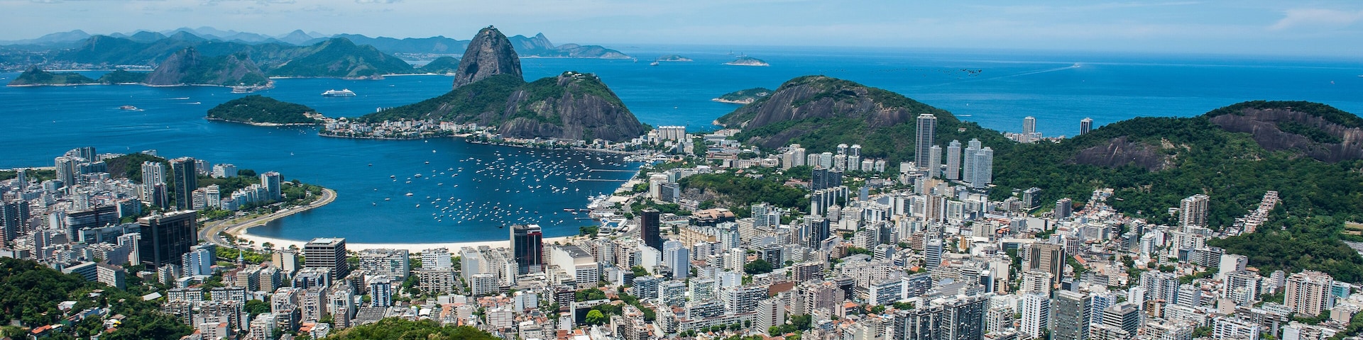 A coastal cityscape with a prominent mountain and a bay.
