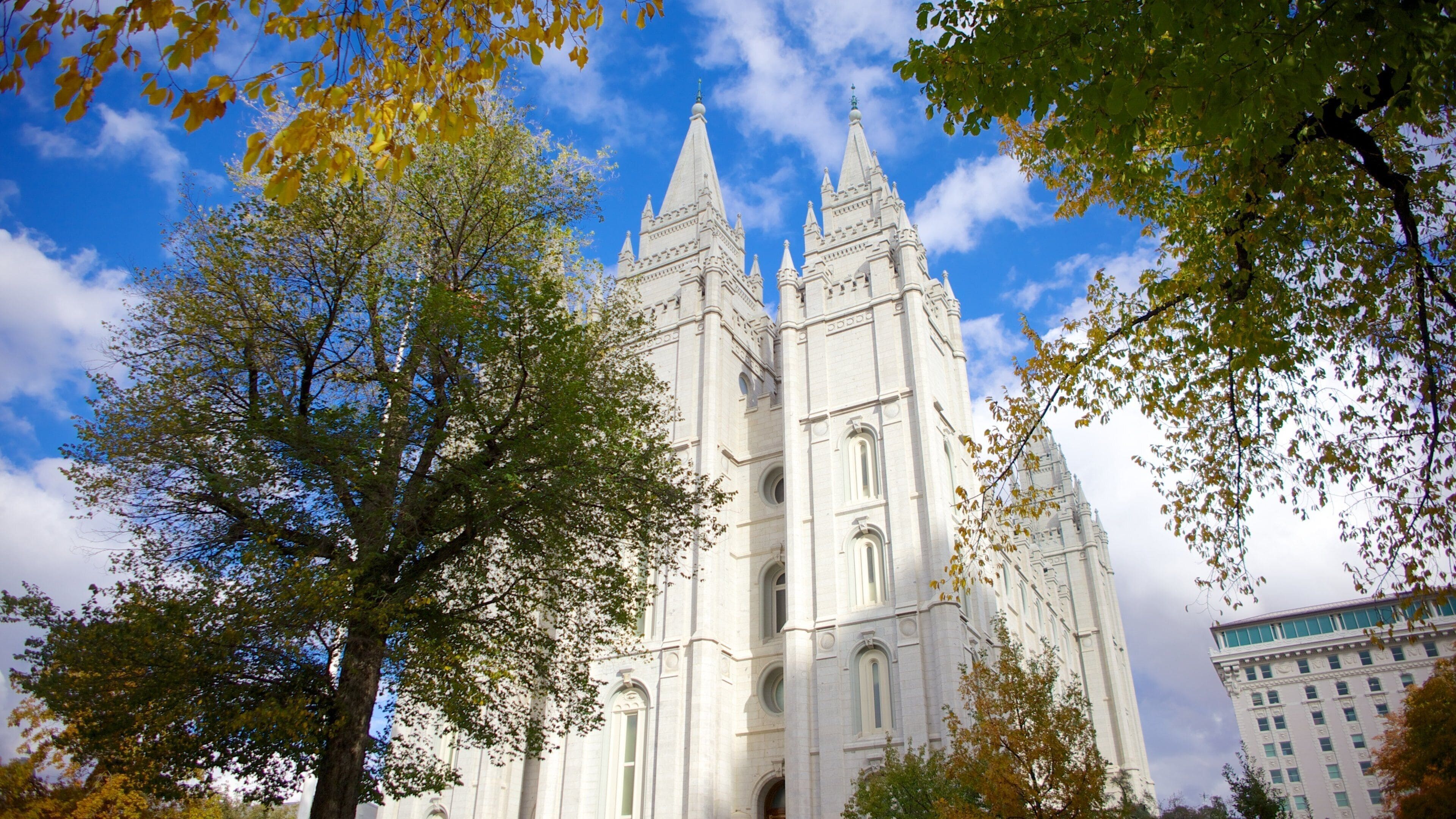 View of the iconic Salt Lake City Temple surrounded by trees and a vibrant sky in Salt Lake City, Utah during autumn