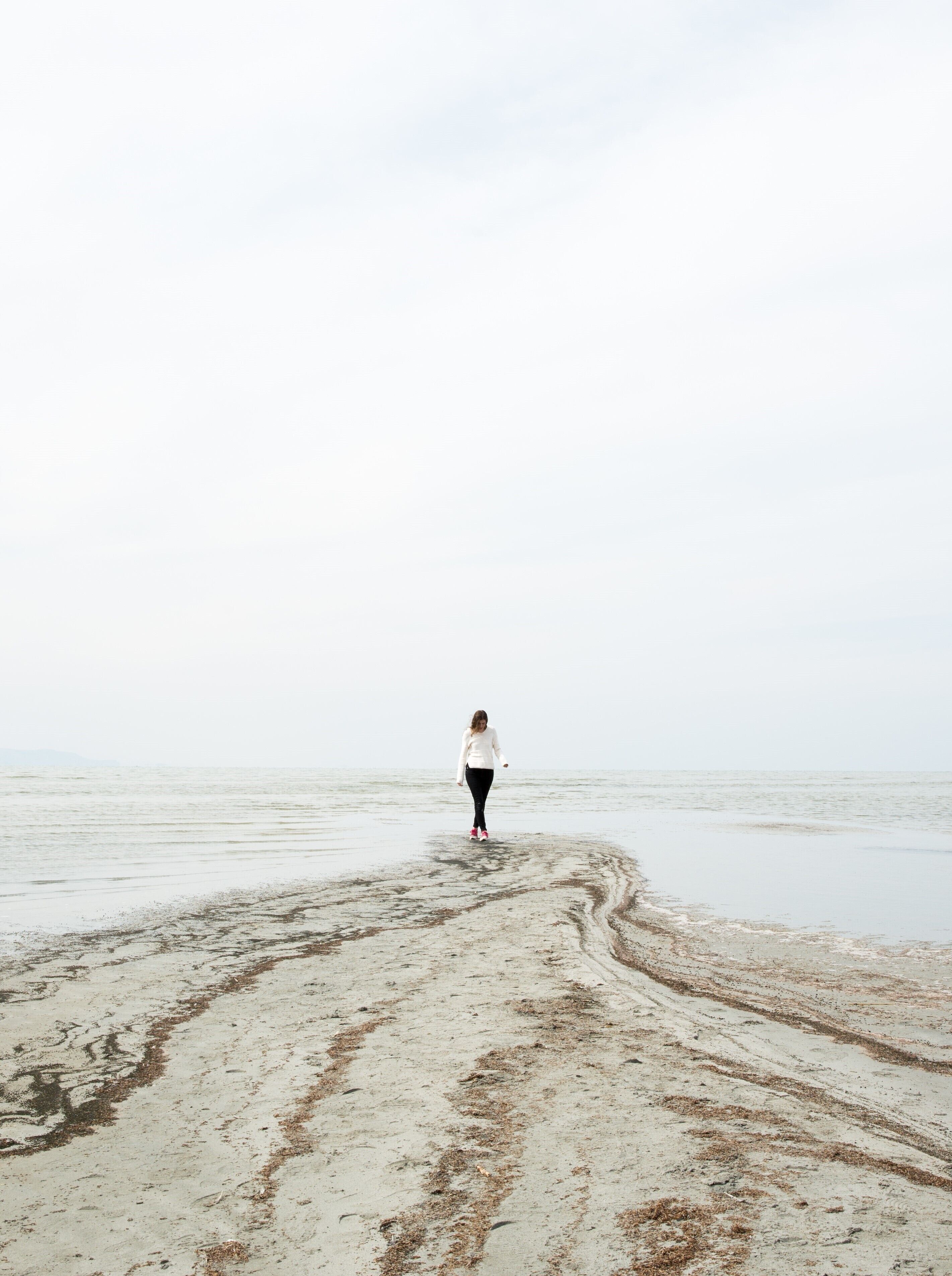 A person walking on a beach with a clear sky.