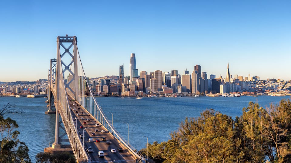 A bridge spanning a river with a city skyline in the background.