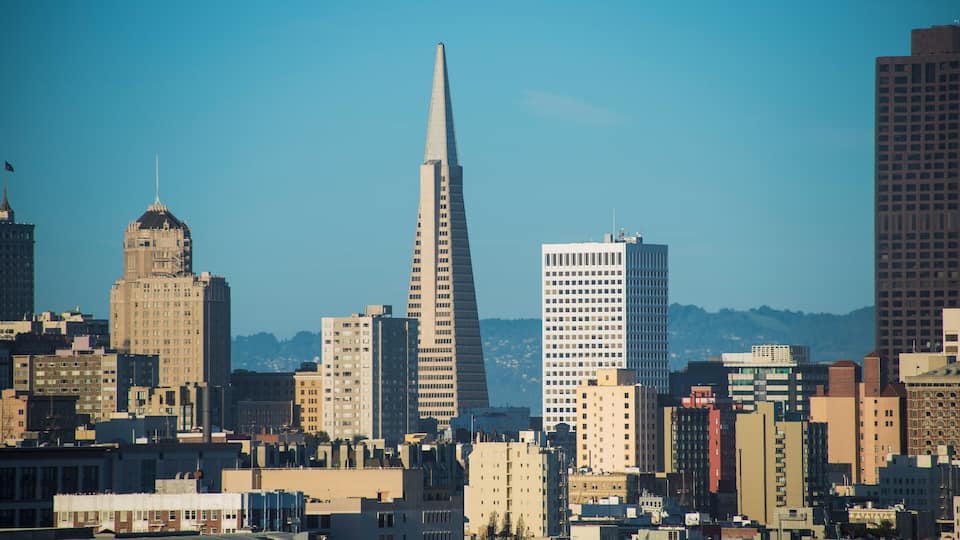 A city skyline with prominent buildings including a tall, pointed skyscraper and a dome-shaped structure.