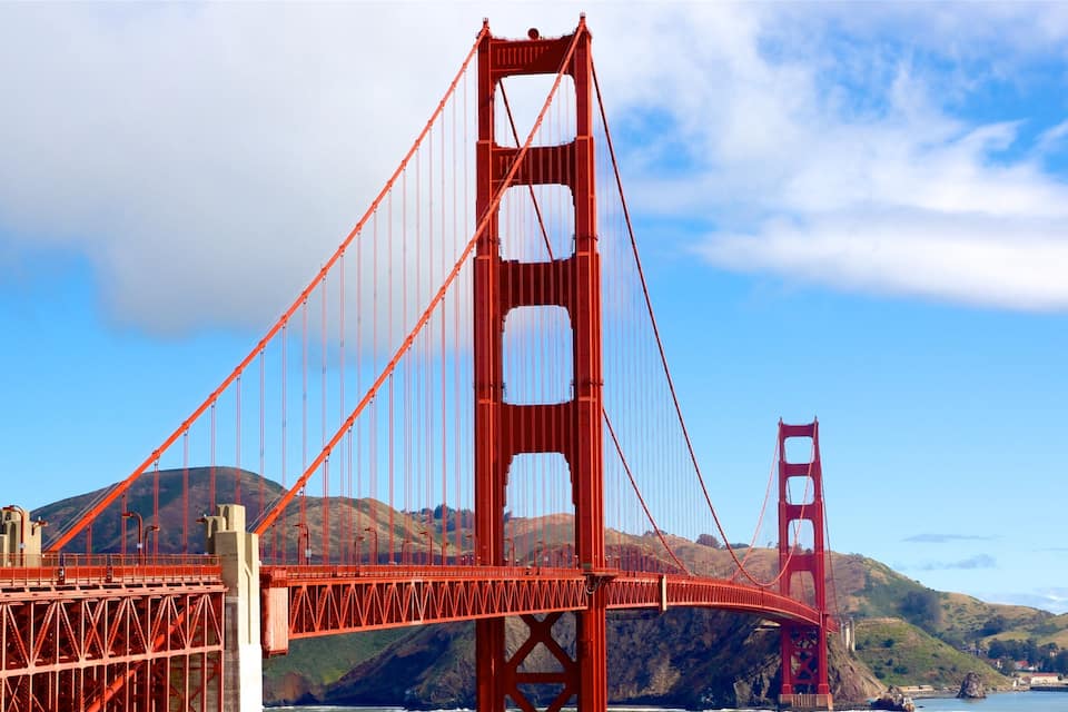 Il Golden Gate Bridge, con le sue torri caratteristiche e i cavi di sospensione, sullo sfondo di colline e della baia di San Francisco.