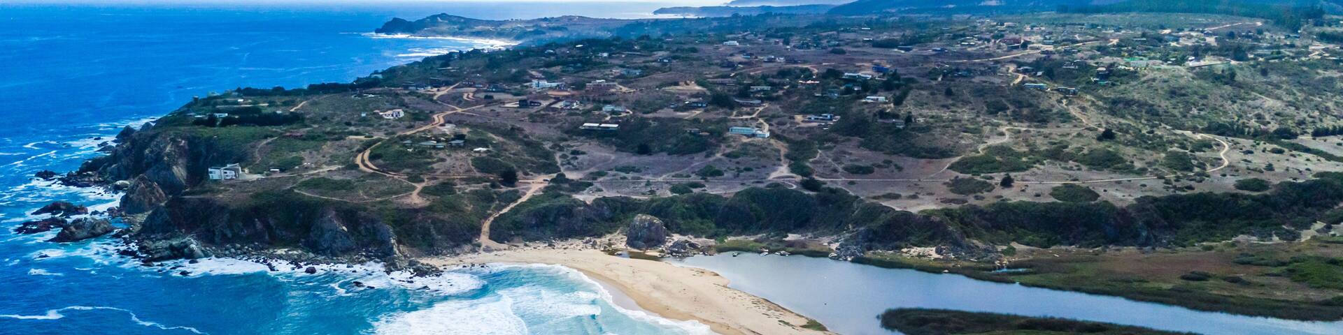 A coastal landscape with a sandy beach, a rocky coastline, and a river flowing through the terrain.
