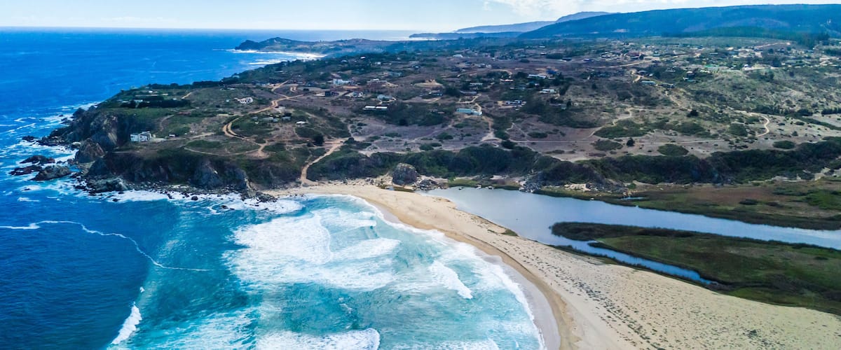 A coastal landscape with a sandy beach, a rocky coastline, and a river flowing through the terrain.