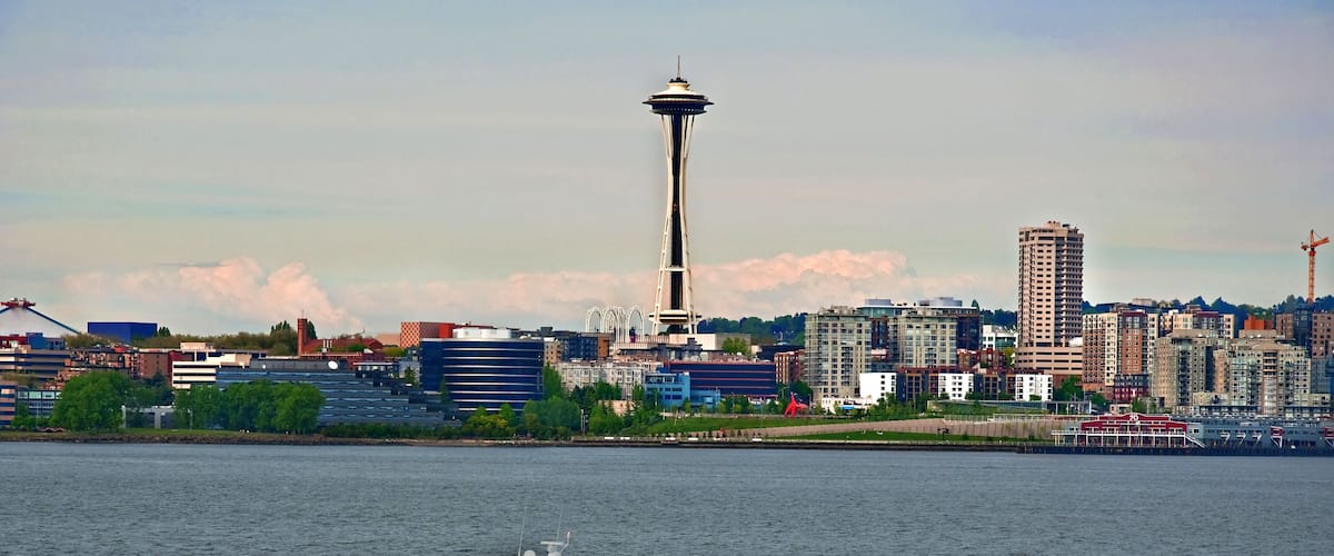A speedboat is rushing by in the foreground of this cityscape of a skyline of Seattle, Washington, in King County. Space needle monument is in the image.