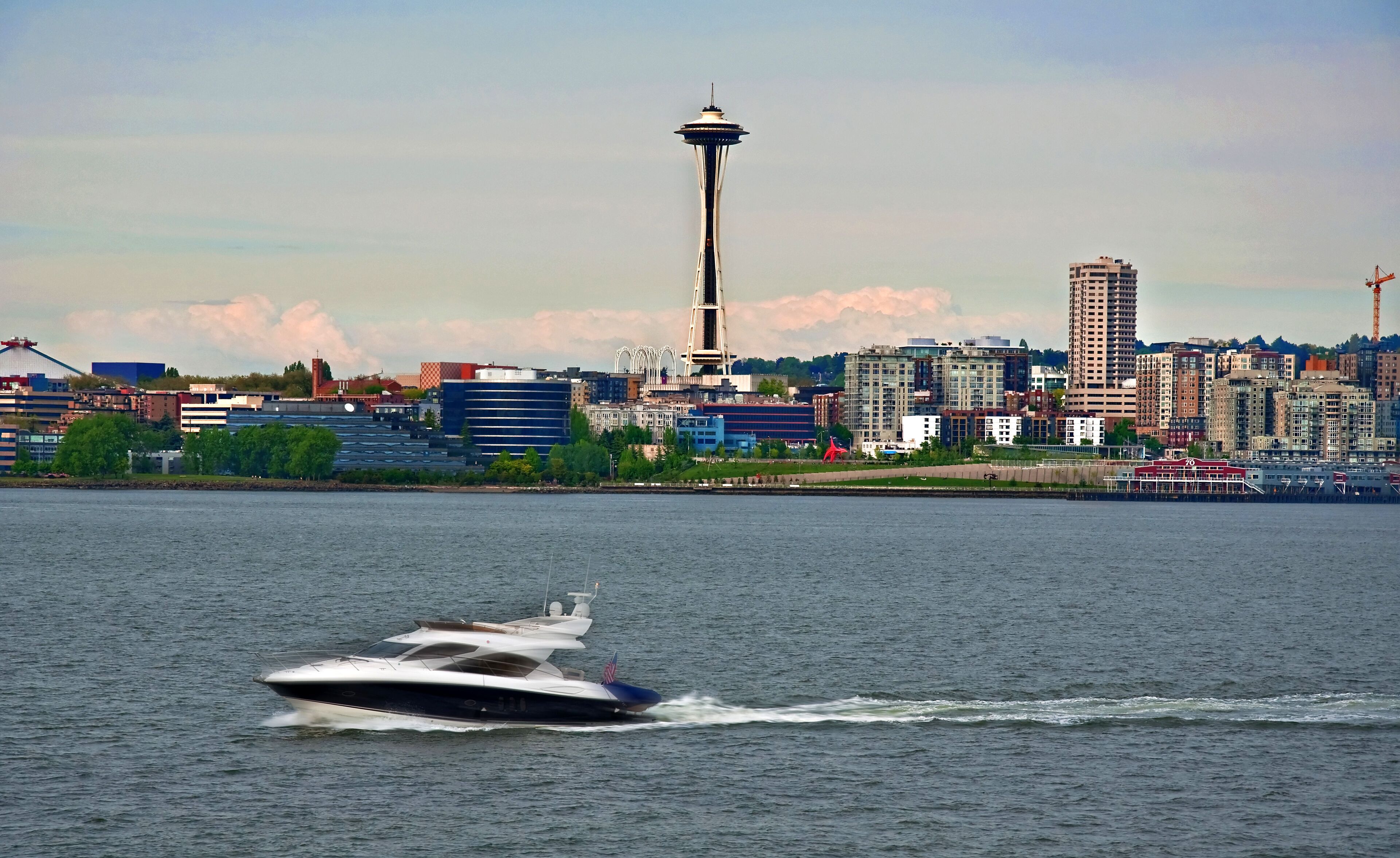 A city skyline with a prominent tower, a body of water, and a speedboat.