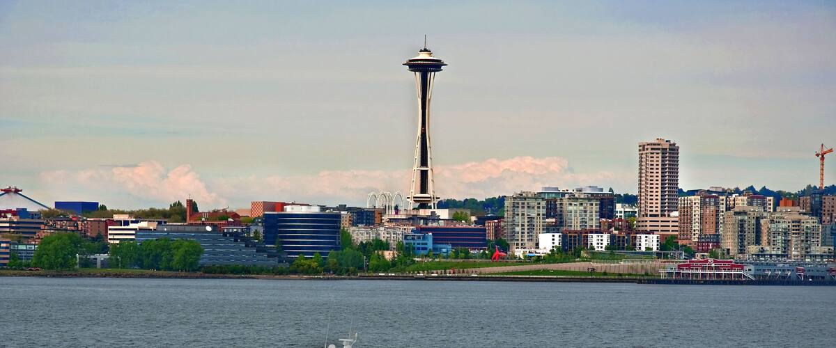 A city skyline with a prominent tower, a body of water, and a speedboat.