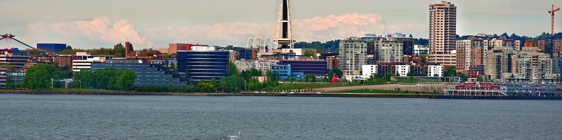 A city skyline with a prominent tower, a body of water, and a speedboat.