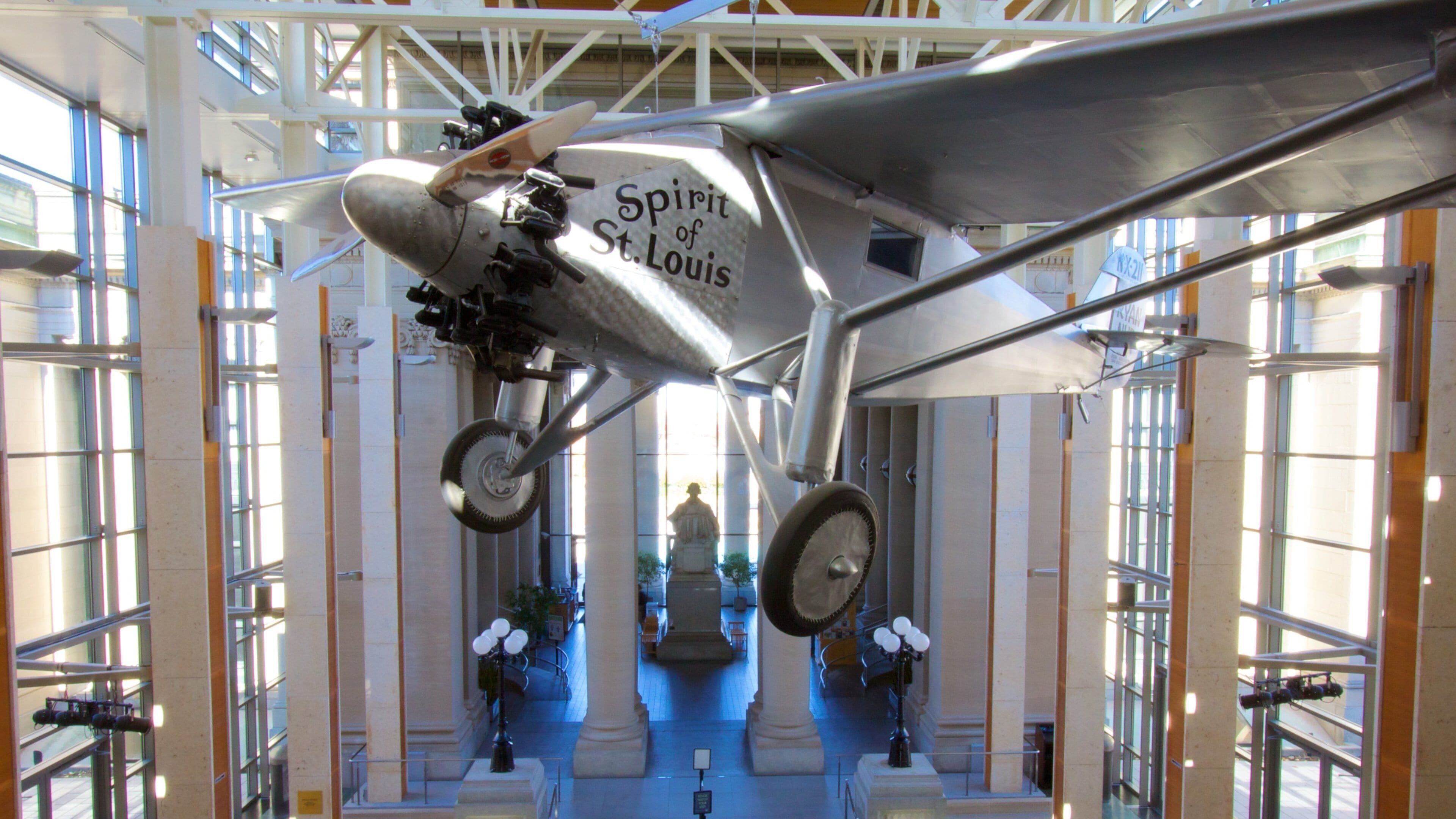 Un avion d’époque, portant l’inscription « Spirit of St. Louis », est suspendu au plafond d’un musée.