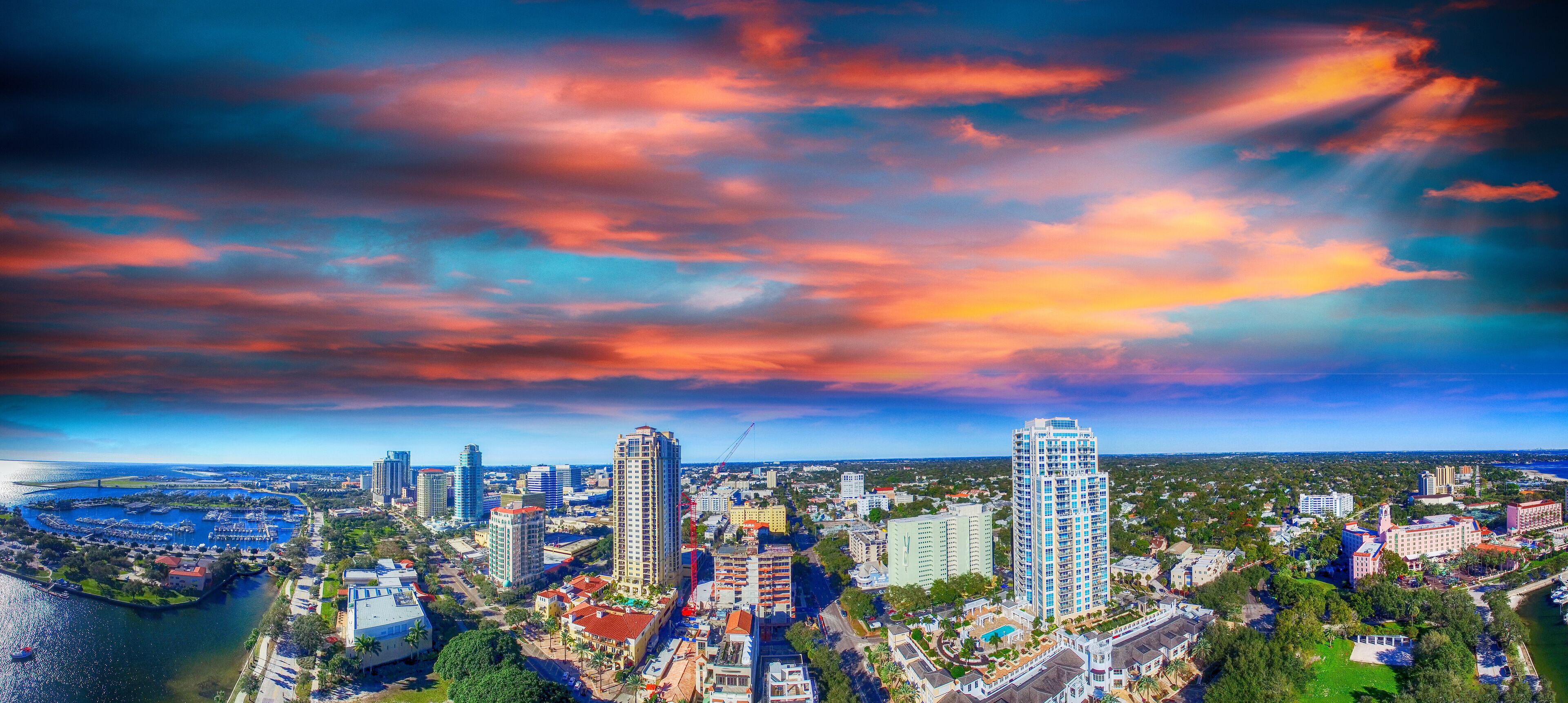 A cityscape with a river, high-rise buildings, and a sunset sky.