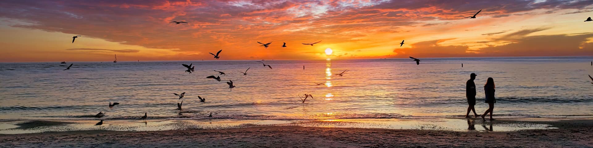A beautiful sunset and silhouette of couple walking along the shoreline on the sand, taken at Clearwater Beach, Florida