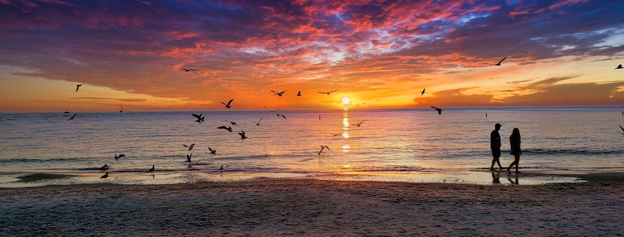 A beautiful sunset and silhouette of couple walking along the shoreline on the sand, taken at Clearwater Beach, Florida