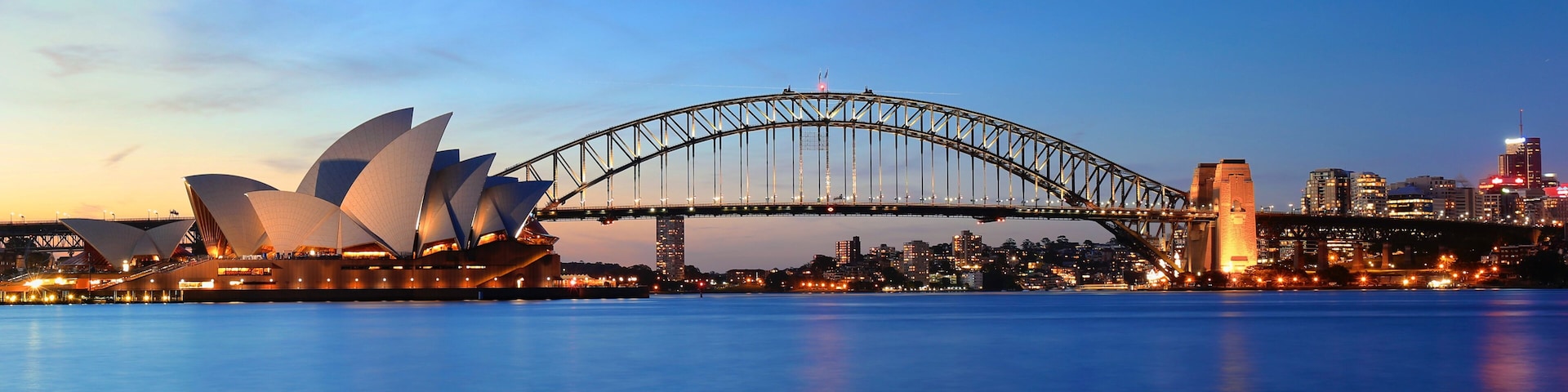 A Casa de Ópera de Sydney e a Ponte Harbour de Sydney ao entardecer.