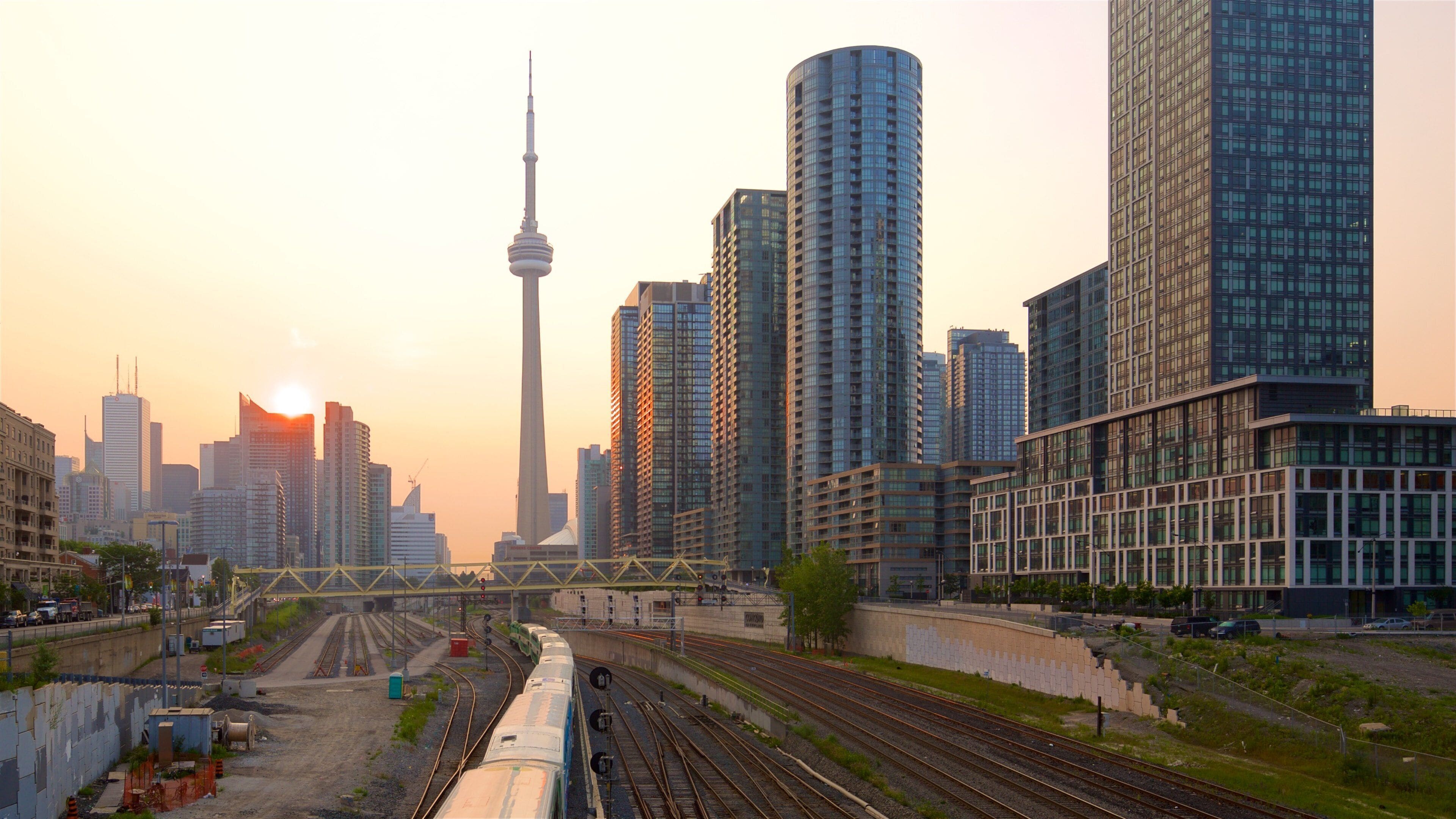 A cityscape with a prominent tower, modern high-rise buildings, and a railway track with a train.