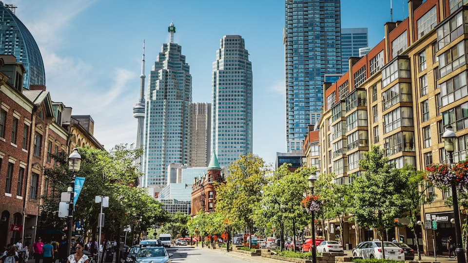 A city street with historic buildings, modern skyscrapers, and a clear blue sky.