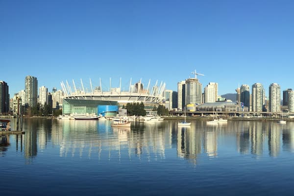 A city skyline with modern buildings, a large spherical structure, and a waterfront with boats.