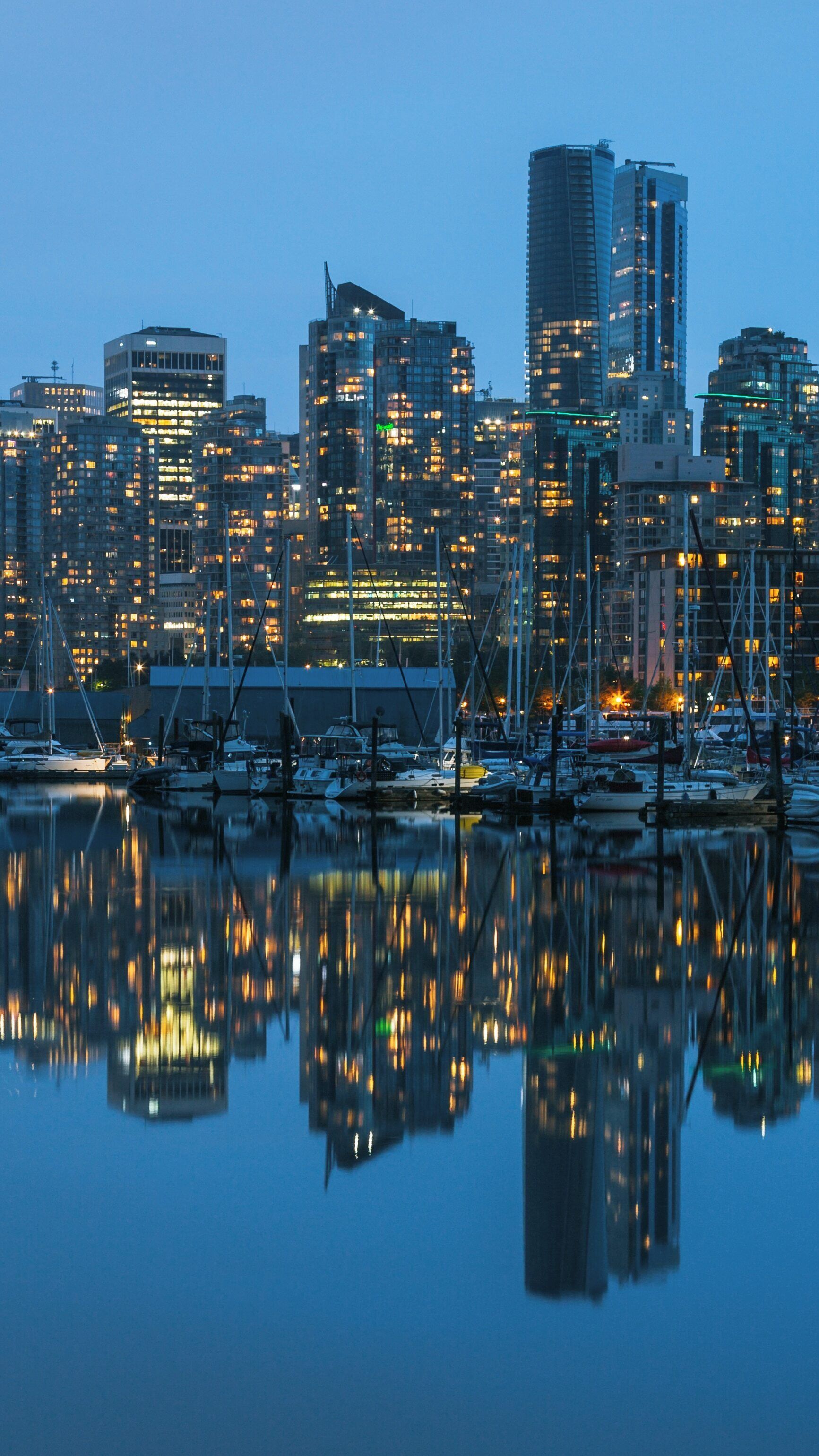 Vibrant city lights reflecting on calm waters at Stanley Park marina in Vancouver, British Columbia during twilight