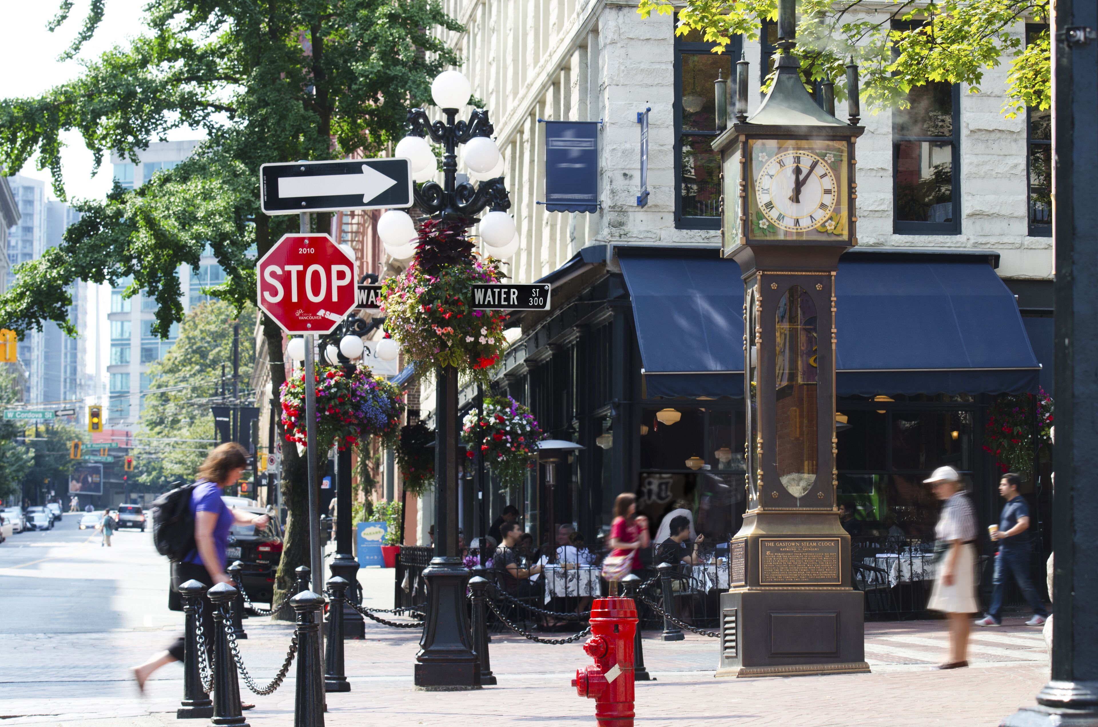 A street with a stop sign, a water street sign, and a clock tower.
