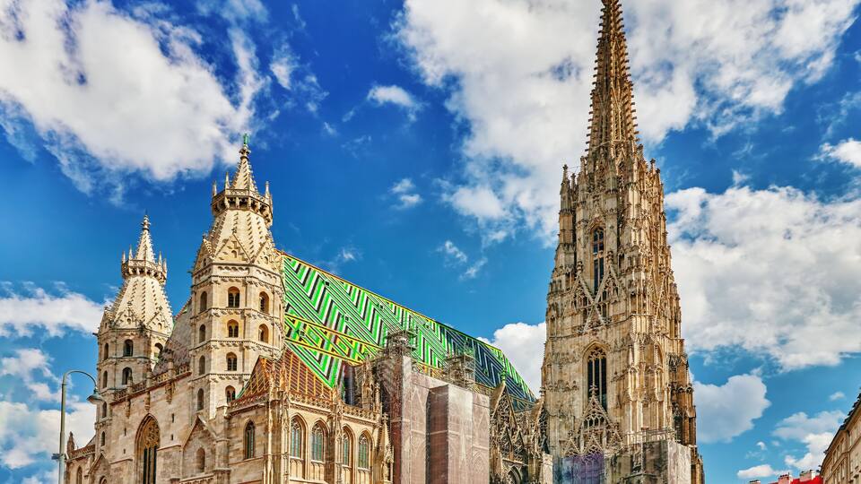 A historic cathedral with intricate architecture, a tall spire, and a colorful roof.