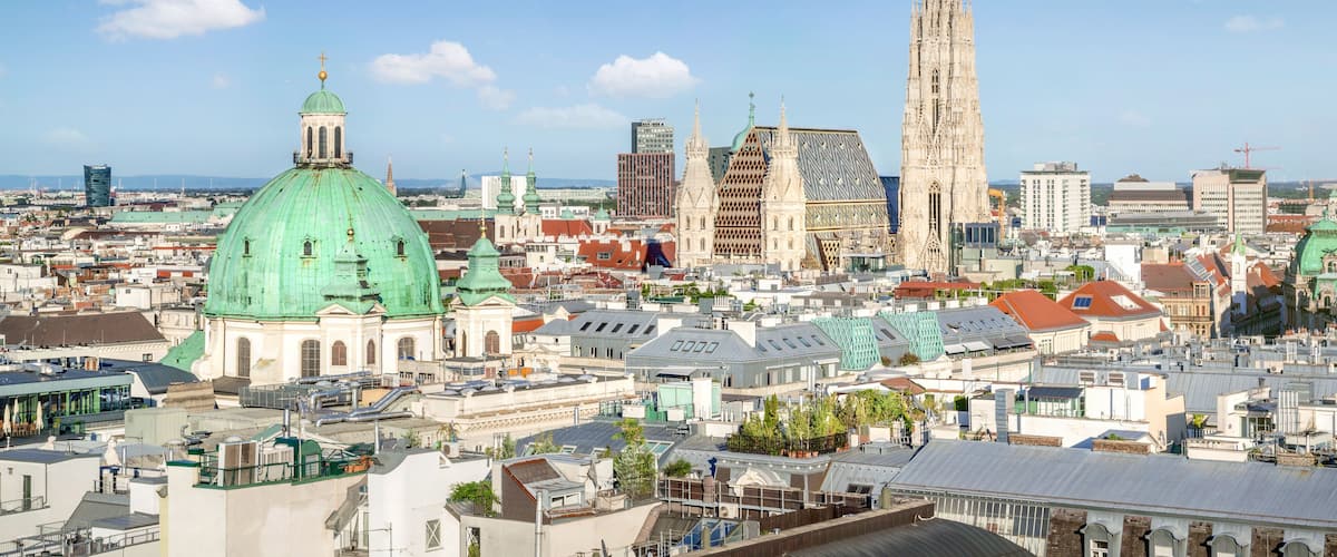 A cityscape with prominent green domed buildings, a tall cathedral, and various modern skyscrapers.
