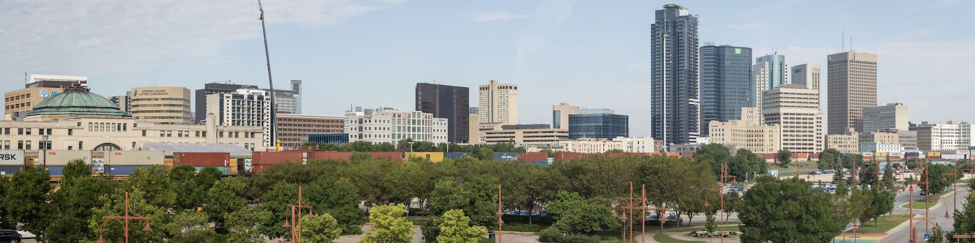 A cityscape with modern high-rise buildings, a large green dome structure, and a park area with trees and a circular plaza.