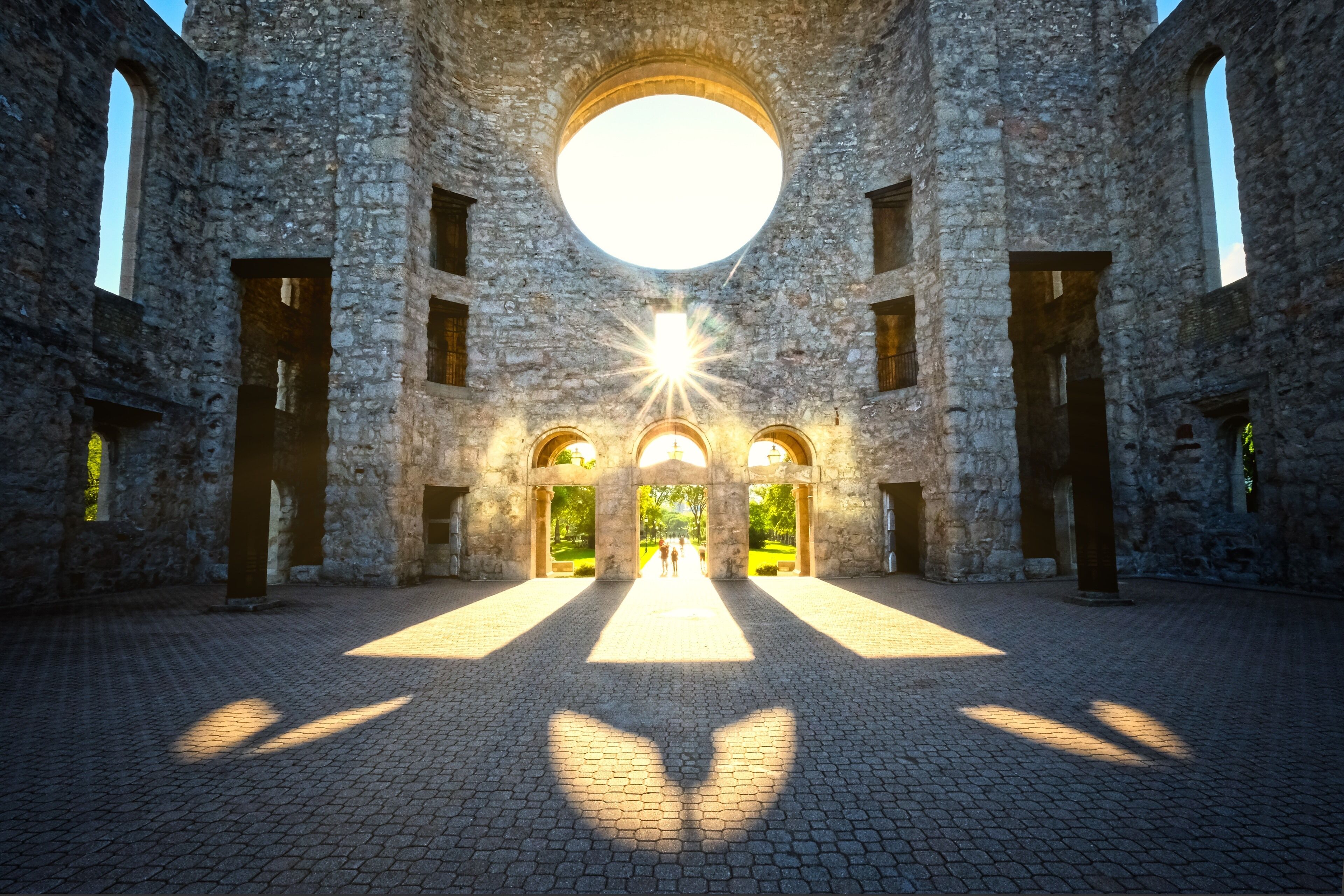 An ancient stone building with a large circular window and arched doorways.