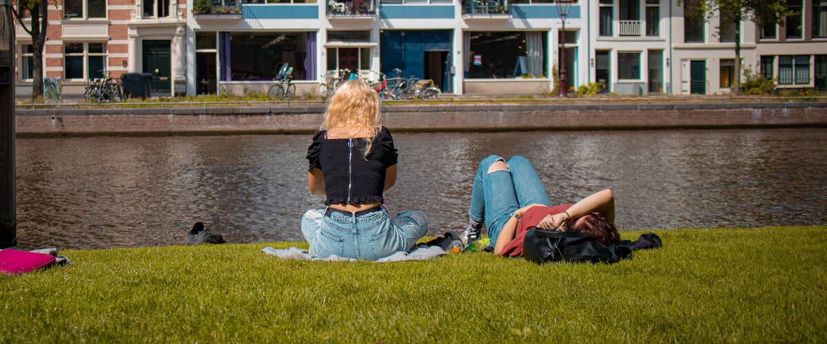 Two women are enjoying rest in the park next to a canal in Amsterdam. Relax in Amsterdam after a hard night or after work.