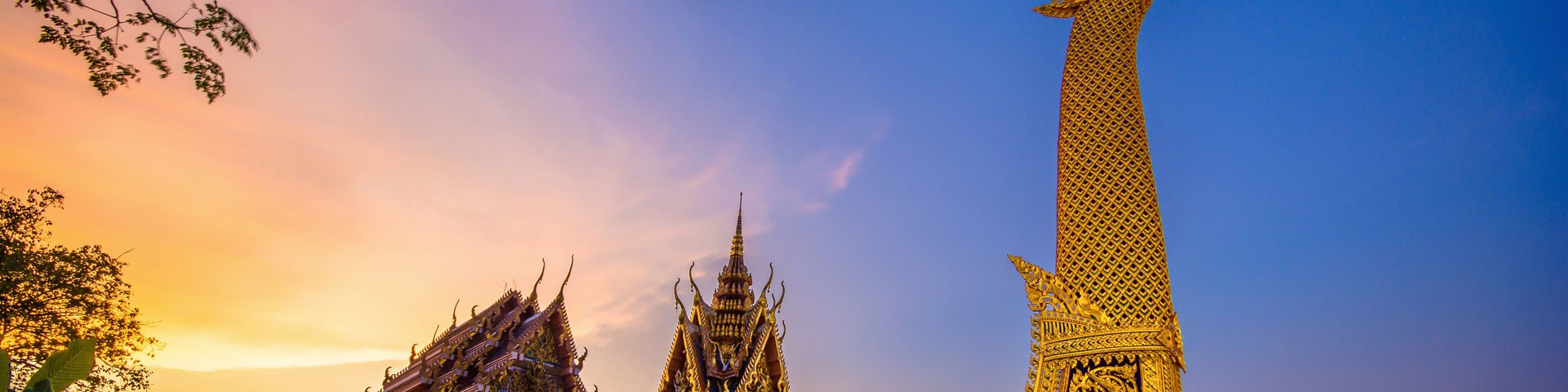 A golden boat-shaped structure with intricate designs, a smaller temple, and a bridge in the background.