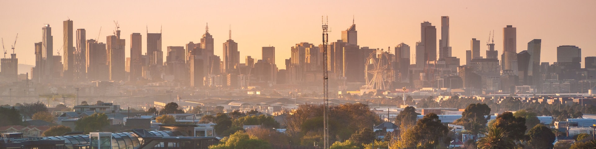 Skyscrapers in Melbourne's CBD in morning mist. Elevated view overlooking residential houses in western suburbs and modern buildings in city. Footscray, VIC Australia.