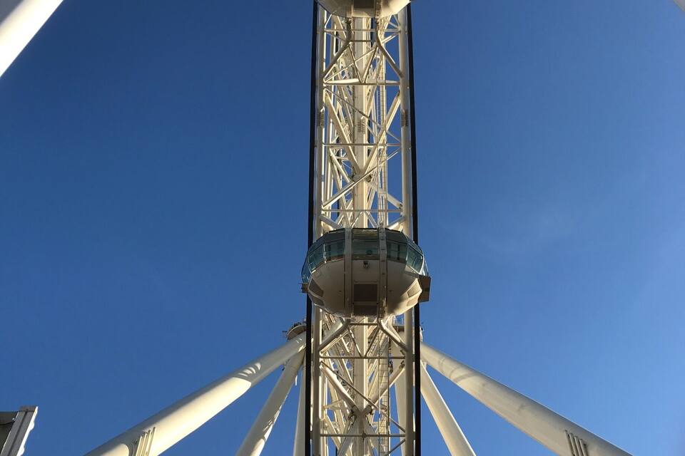 A tall Ferris wheel with a clear blue sky in the background.